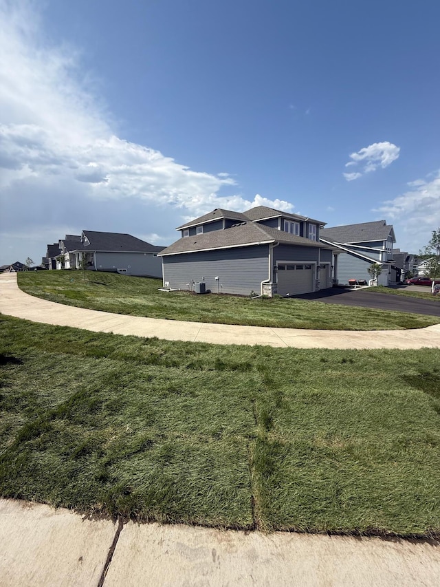 10071 Arrowwood Trl, Woodbury, MN 55129 - view of side of property with asphalt driveway, a yard, and a garage