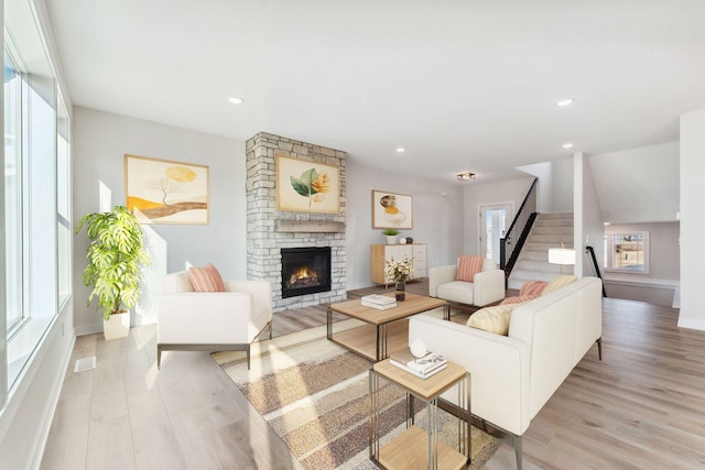 10071 Arrowwood Trl, Woodbury, MN 55129 - living area featuring a stone fireplace, light wood-style flooring, stairs, and recessed lighting