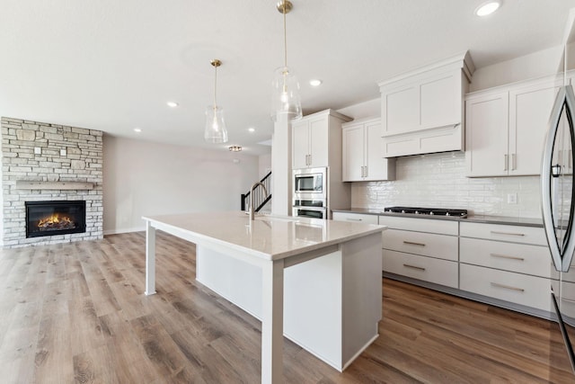 10071 Arrowwood Trl, Woodbury, MN 55129 - kitchen with stainless steel appliances, open floor plan, decorative backsplash, recessed lighting, and wood finished floors