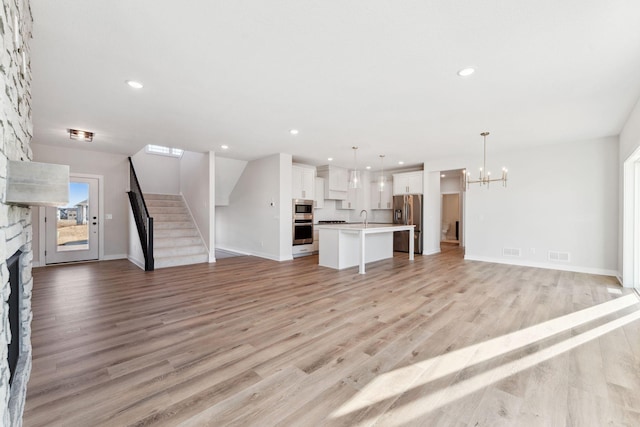 10071 Arrowwood Trl, Woodbury, MN 55129 - unfurnished living room featuring a fireplace, a chandelier, light wood-style floors, stairs, and recessed lighting