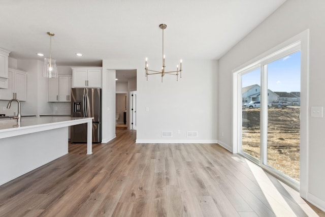 10071 Arrowwood Trl, Woodbury, MN 55129 - kitchen featuring stainless steel refrigerator with ice dispenser, light wood finished floors, light countertops, a chandelier, and recessed lighting