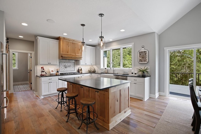 16999 Dakota St NW, Andover, MN 55304 - kitchen with decorative backsplash, dark countertops, light wood-style floors, and a kitchen bar