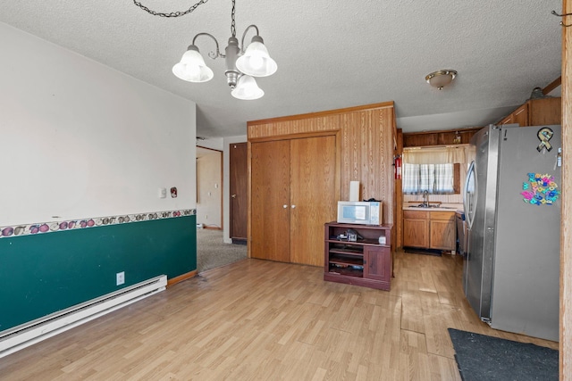 27928 Verdin St NW, Isanti, MN 55040 - kitchen featuring freestanding refrigerator, light wood-style flooring, a notable chandelier, white microwave, and baseboard heating