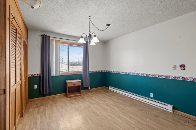 27928 Verdin St NW, Isanti, MN 55040 - spare room with light wood-type flooring, an inviting chandelier, baseboards, a textured ceiling, and a baseboard radiator