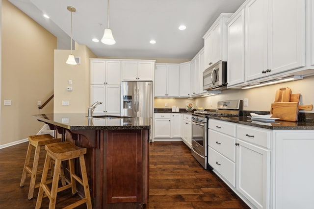 8127 Virginia Pl, Savage, MN 55378 - kitchen with appliances with stainless steel finishes, dark wood-style flooring, a sink, recessed lighting, and a kitchen bar