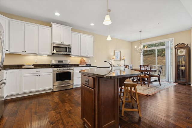 8127 Virginia Pl, Savage, MN 55378 - kitchen featuring stainless steel appliances, dark wood-style flooring, a sink, a breakfast bar area, and white cabinets