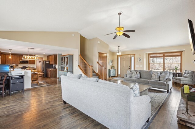 living area with a ceiling fan, dark wood-type flooring, stairs, and vaulted ceiling
