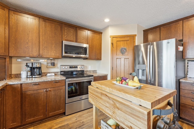 kitchen featuring brown cabinets, appliances with stainless steel finishes, and light wood finished floors