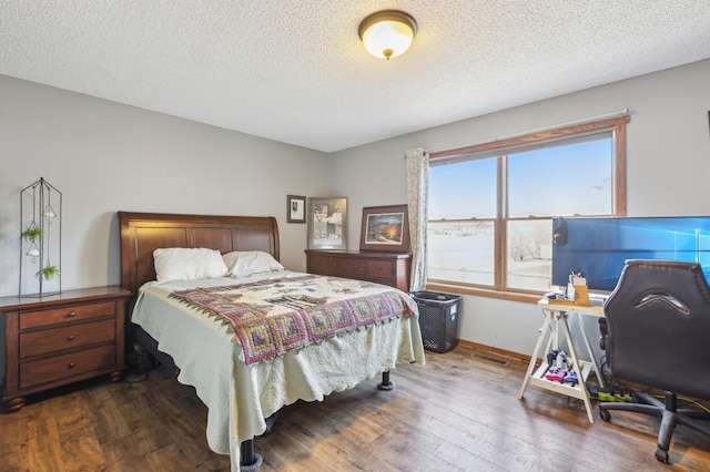 bedroom with baseboards, wood-type flooring, a textured ceiling, and visible vents