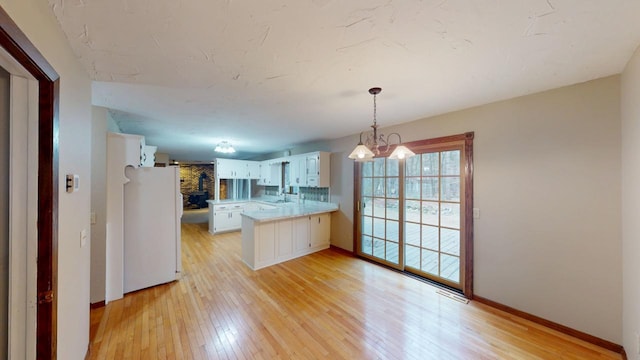 2342 75th Ave, Princeton, MN 55371 - kitchen with freestanding refrigerator, a peninsula, light countertops, a sink, and light wood finished floors