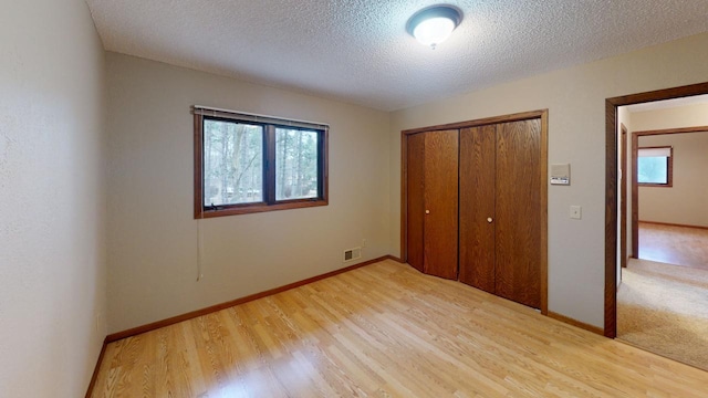 2342 75th Ave, Princeton, MN 55371 - unfurnished bedroom featuring light wood-style flooring, a closet, multiple windows, and a textured ceiling