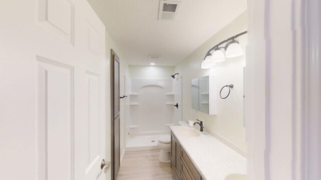 2342 75th Ave, Princeton, MN 55371 - full bath featuring toilet, a stall shower, vanity, a textured ceiling, and wood finished floors