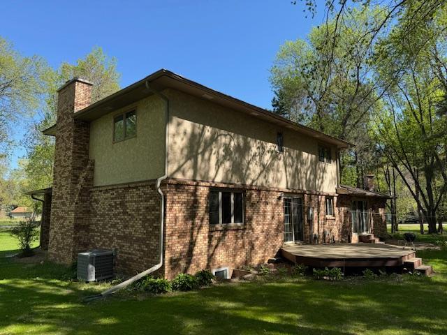 2342 75th Ave, Princeton, MN 55371 - view of property exterior with a chimney, a deck, a yard, stucco siding, and central AC