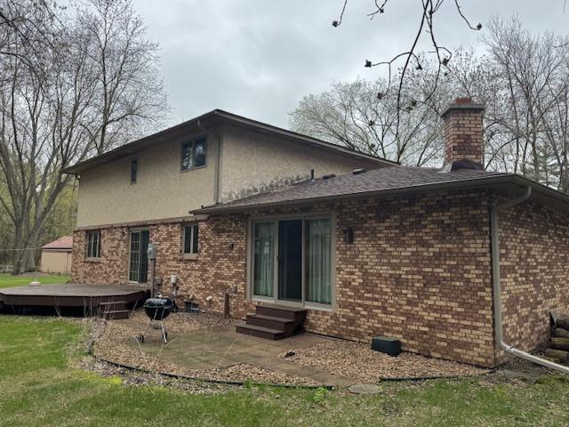 2342 75th Ave, Princeton, MN 55371 - rear view of property featuring a wooden deck, a chimney, entry steps, a patio area, and stucco siding