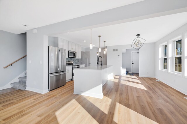 1903 Thomas Ave N, Minneapolis, MN 55411 - kitchen with white cabinets, stainless steel appliances, light wood finished floors, a sink, and backsplash