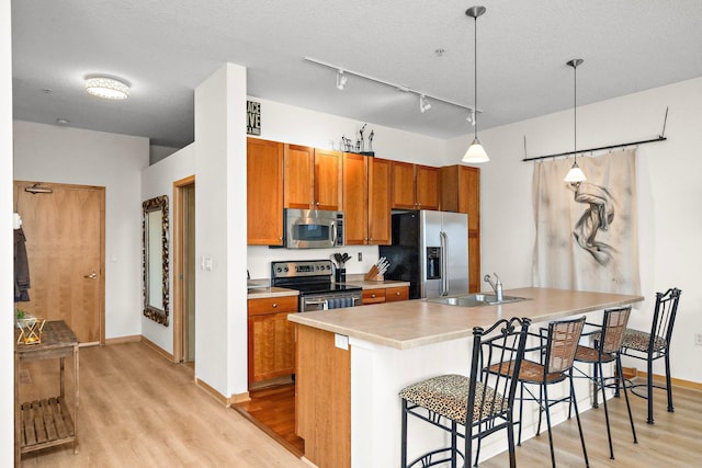 4525 Park Commons Dr Unit 221, Saint Louis Park, MN 55416 - kitchen with a breakfast bar, a sink, stainless steel appliances, brown cabinetry, and light wood-style floors