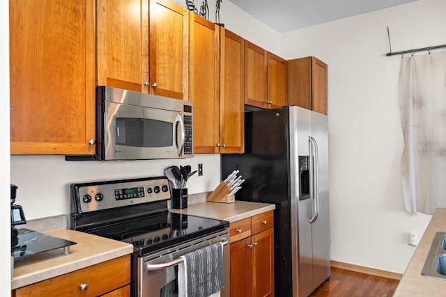 4525 Park Commons Dr Unit 221, Saint Louis Park, MN 55416 - kitchen with stainless steel appliances, brown cabinetry, baseboards, dark wood finished floors, and light countertops