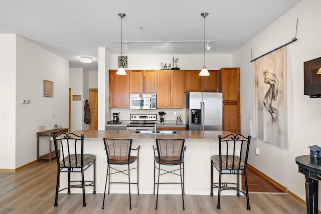 4525 Park Commons Dr Unit 221, Saint Louis Park, MN 55416 - kitchen featuring light wood finished floors, a sink, stainless steel appliances, a kitchen breakfast bar, and decorative light fixtures