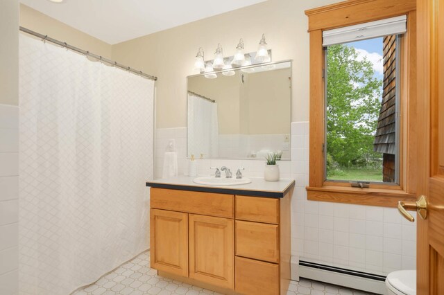 12697 177th St N, May Twp, MN 55047 - bathroom featuring a baseboard heating unit, tile walls, vanity, toilet, and a wainscoted wall