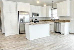 260 Spring St, Osceola, WI 54020 - kitchen with white cabinetry, light wood-style flooring, stainless steel appliances, and a center island