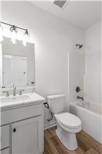260 Spring St, Osceola, WI 54020 - bathroom featuring wood finished floors,  shower combination, toilet, and vanity