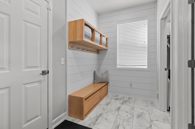 mudroom featuring marble finish floor, wooden walls, and plenty of natural light