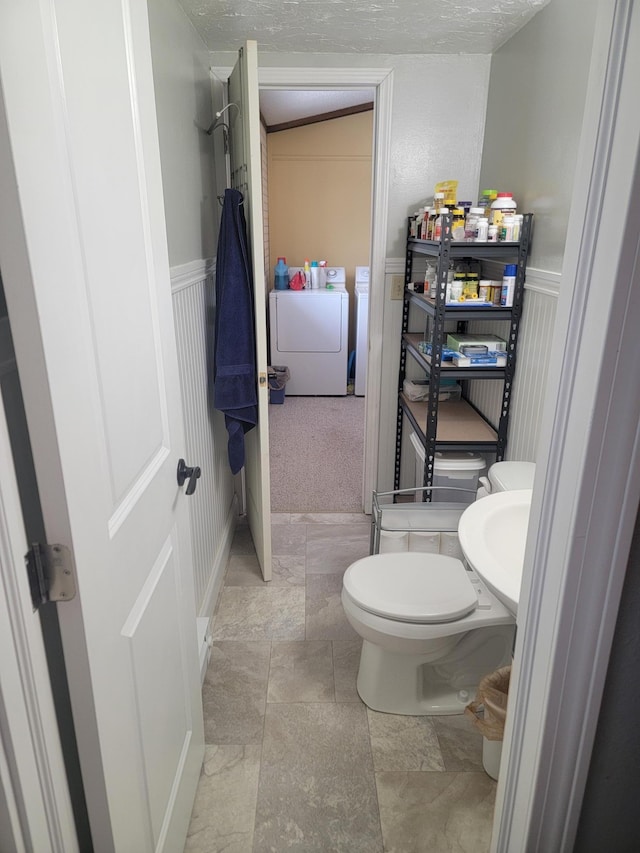 29829 400th Ave, Roseau, MN 56751 - bathroom with washer and clothes dryer, toilet, a decorative wall, a wainscoted wall, and a textured ceiling