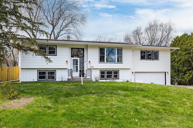 bi-level home featuring an attached garage, fence, and a front lawn