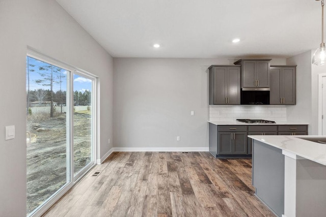 kitchen featuring gray cabinetry, wood finished floors, tasteful backsplash, light countertops, and recessed lighting