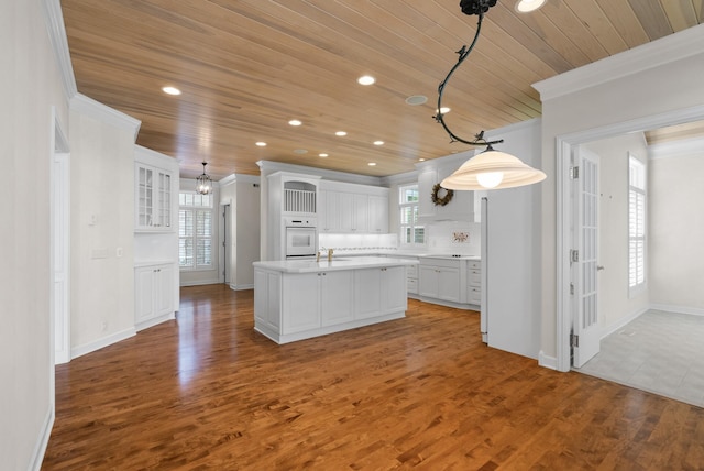 1505 Edgewater Ave, Arden Hills, MN 55112 - kitchen featuring white oven, wooden ceiling, white cabinets, an island with sink, and crown molding