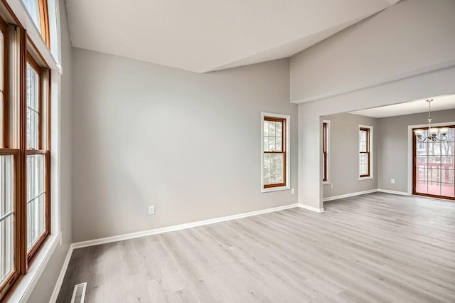 5298 Park Dr, Savage, MN 55378 - unfurnished room with visible vents, baseboards, a chandelier, lofted ceiling, and wood finished floors