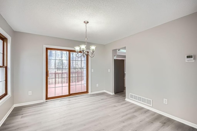 5298 Park Dr, Savage, MN 55378 - unfurnished dining area featuring a textured ceiling, light wood-style flooring, visible vents, and a chandelier