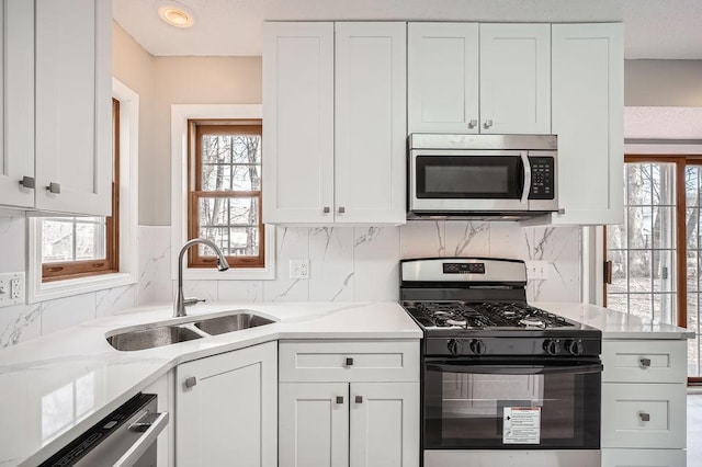 5298 Park Dr, Savage, MN 55378 - kitchen with light stone counters, a sink, stainless steel appliances, white cabinets, and backsplash