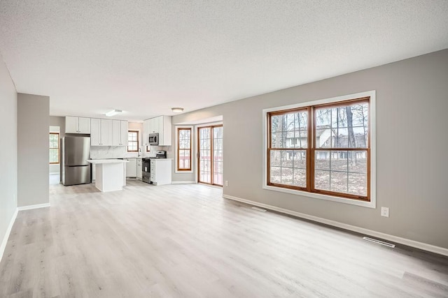 5298 Park Dr, Savage, MN 55378 - unfurnished living room with visible vents, light wood-style flooring, a textured ceiling, and baseboards