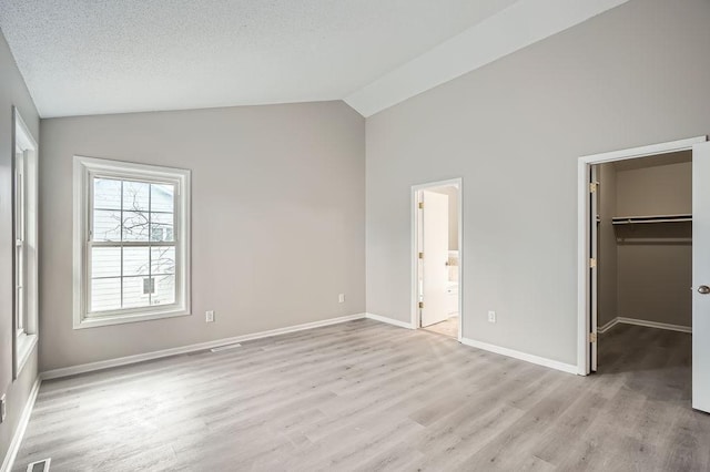 5298 Park Dr, Savage, MN 55378 - unfurnished bedroom featuring a walk in closet, lofted ceiling, light wood-style floors, and baseboards