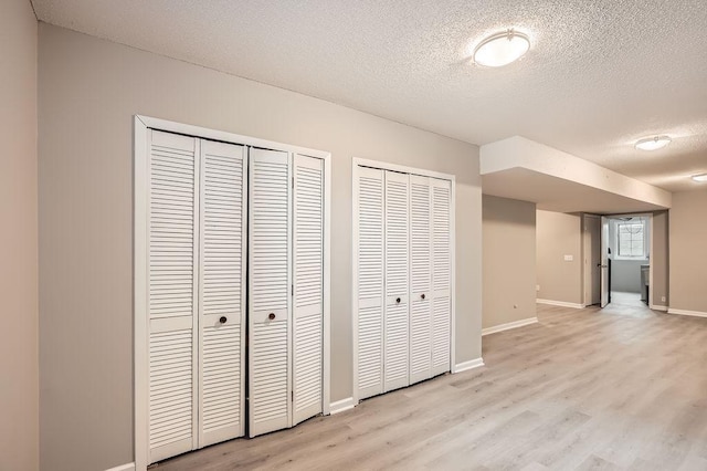 5298 Park Dr, Savage, MN 55378 - unfurnished bedroom with light wood-type flooring, baseboards, two closets, and a textured ceiling