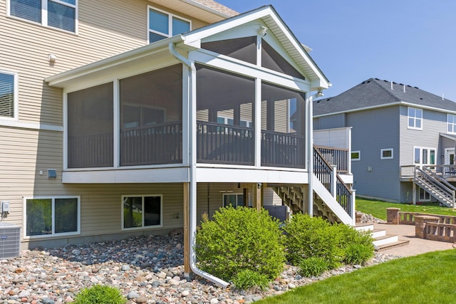 rear view of house with stairs, a sunroom, and central AC unit
