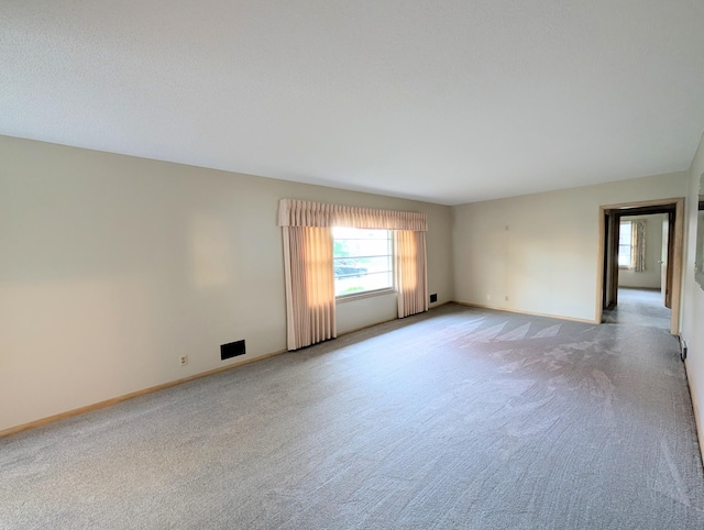 unfurnished room featuring light carpet, plenty of natural light, and baseboards