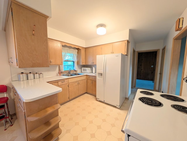 kitchen featuring white appliances, a sink, light countertops, light floors, and a peninsula