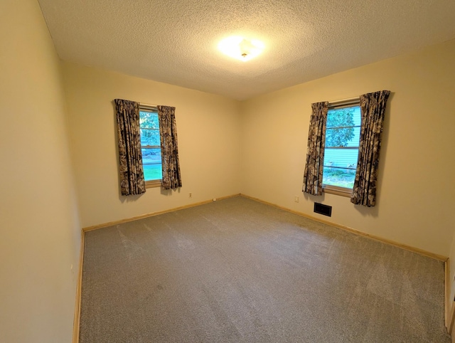 carpeted spare room with a textured ceiling and baseboards