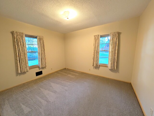 spare room with carpet flooring, a textured ceiling, and baseboards