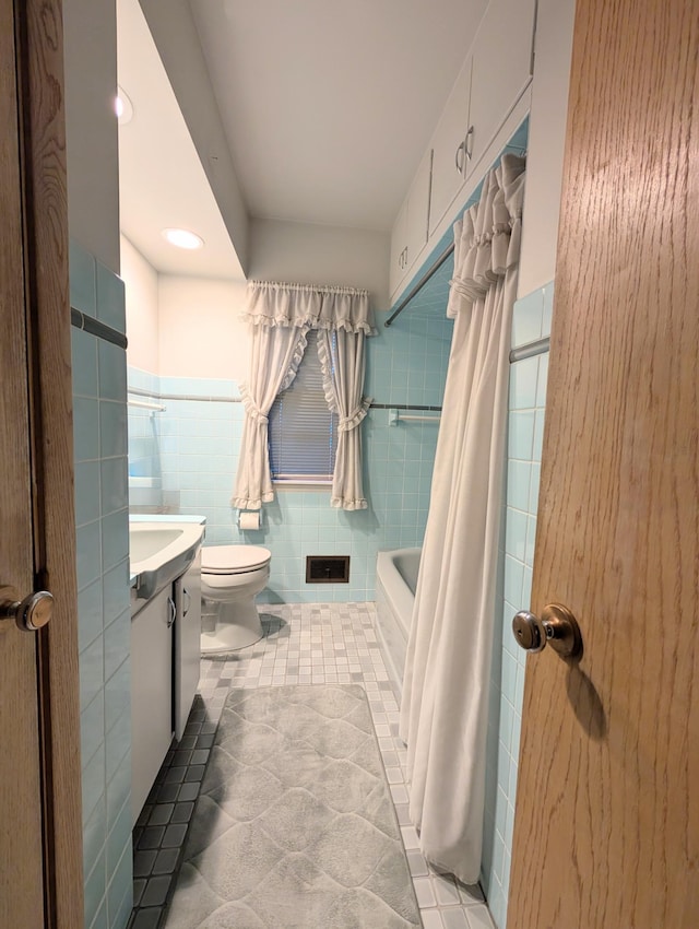 bathroom with tile walls, vanity, toilet, tile patterned flooring, and a wainscoted wall