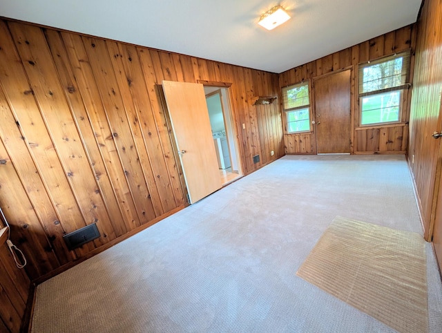 unfurnished room featuring carpet flooring and wood walls