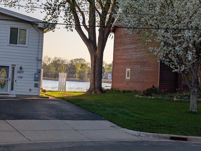 property exterior at dusk featuring a water view and a yard