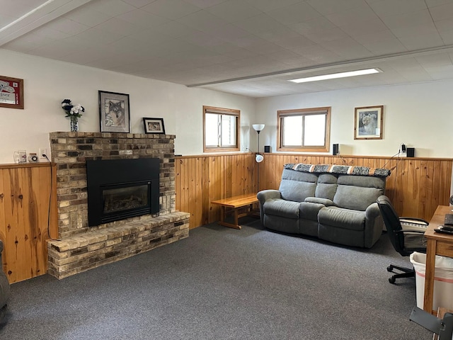 living room featuring carpet floors, wood walls, wainscoting, and a brick fireplace