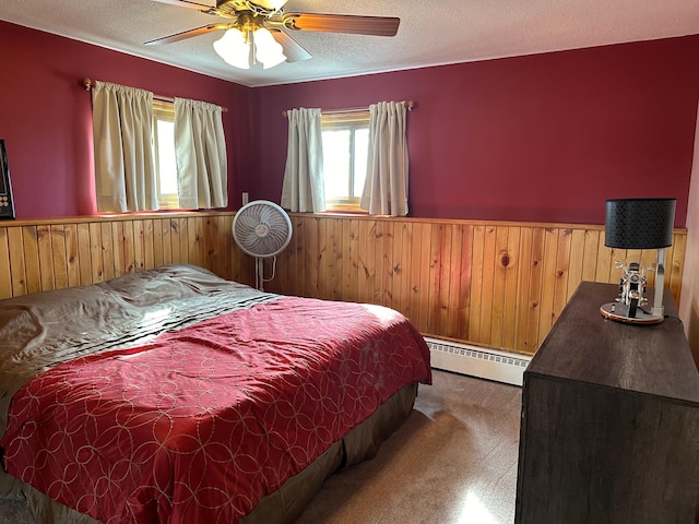 bedroom with wood walls, a baseboard heating unit, wainscoting, and carpet