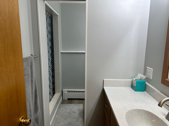 full bath with vanity, a baseboard radiator, wood finished floors, and a shower stall