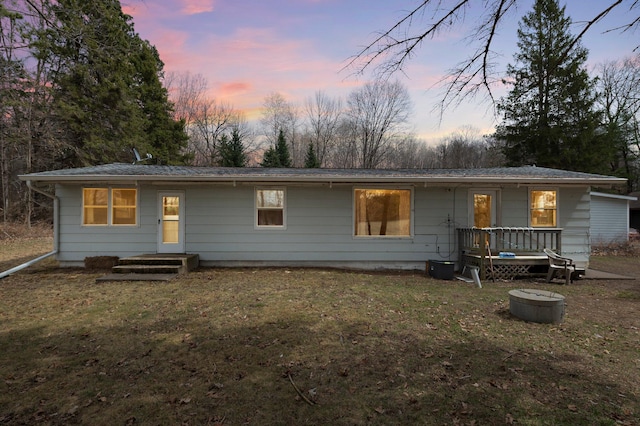 back of house at dusk featuring a lawn