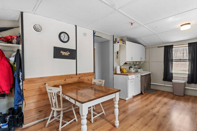 dining space with light wood finished floors and a drop ceiling