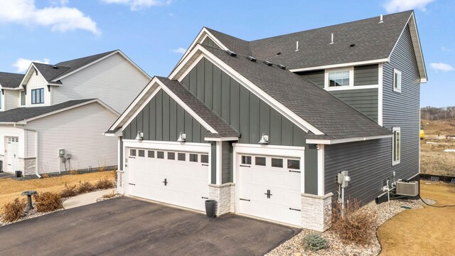 view of property exterior featuring aphalt driveway, board and batten siding, and roof with shingles